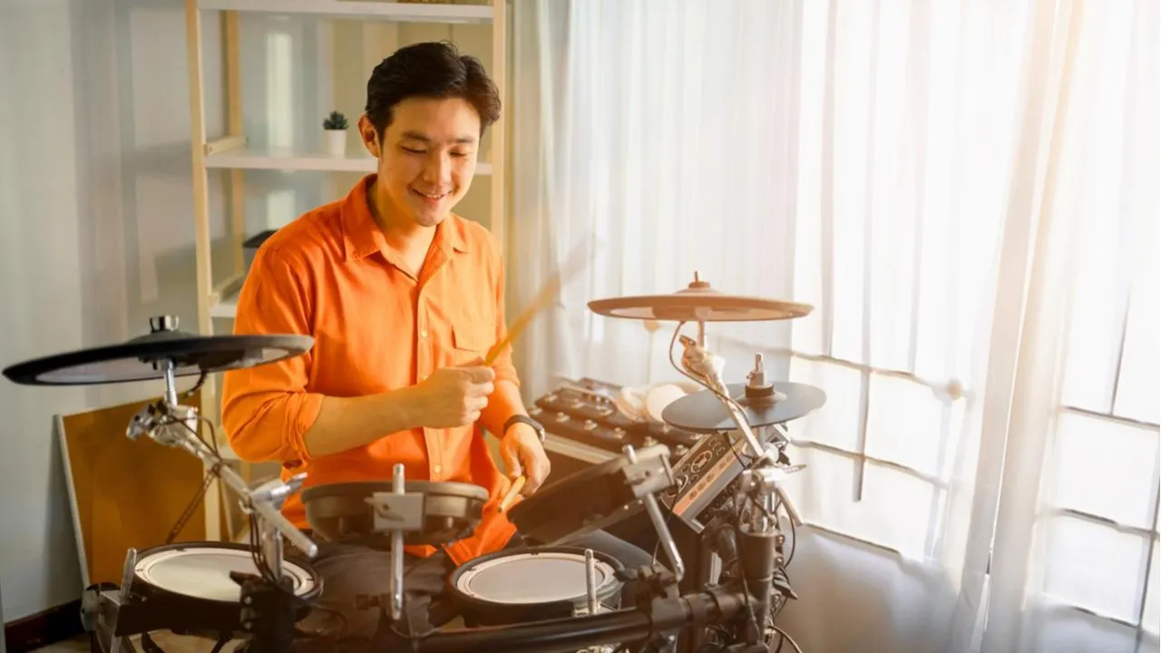 FWD custom stock - Young man playing a set of drums in his home.webp
