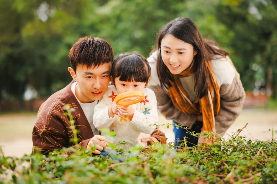 A_couple_doing_an_exploration_with_their_young_child_with_a_magnifying_glass_in_the_park.webp