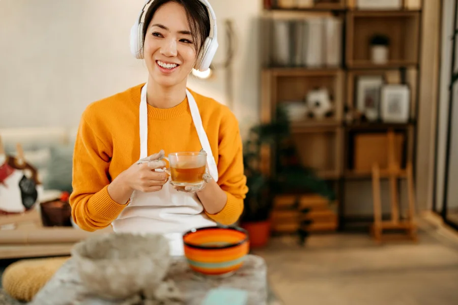 Young_woman_drinking_coffee_in_her_home_workshop_where_she_makes_clay_objects.webp